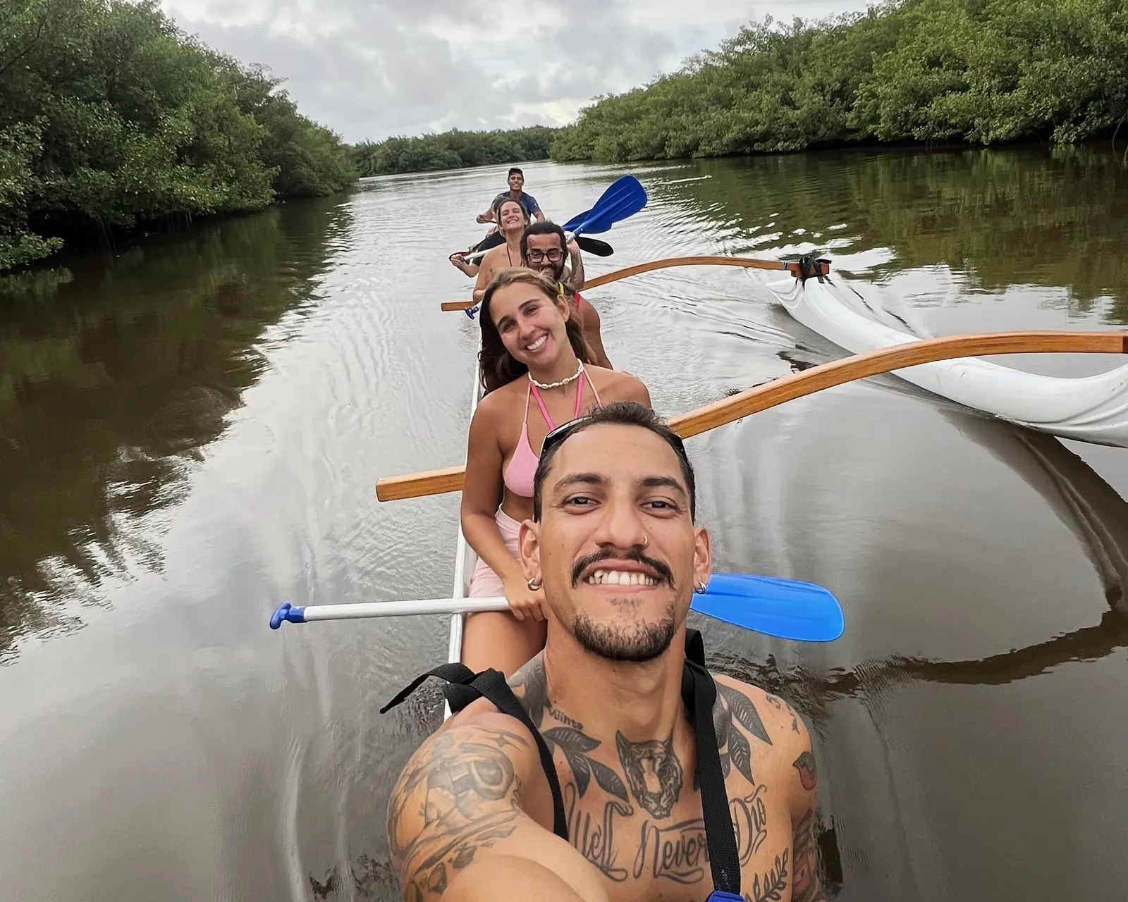 Grupo sonriente a bordo de una canoa hawaiana en un canal de manglar de la Laguna Guaraíras, en Tibau do Sul (RN, Brasil)