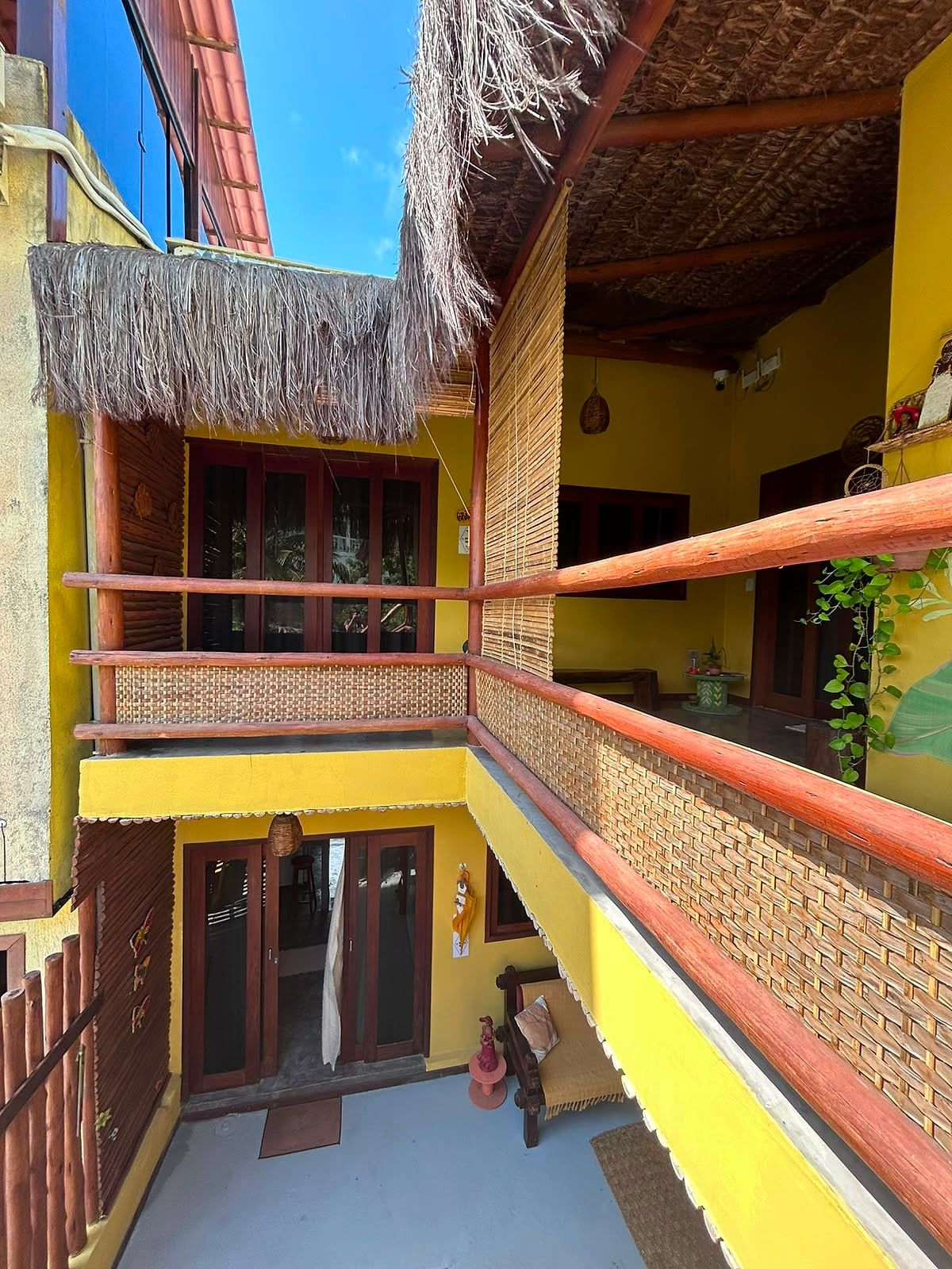 Pátio interno da Vila Canela, com varandas de madeira e paredes amarelas